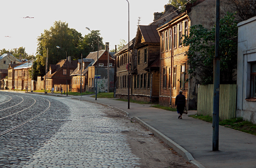Cobblestone street lined with wooden buildings in Maskavas Forstate at dusk